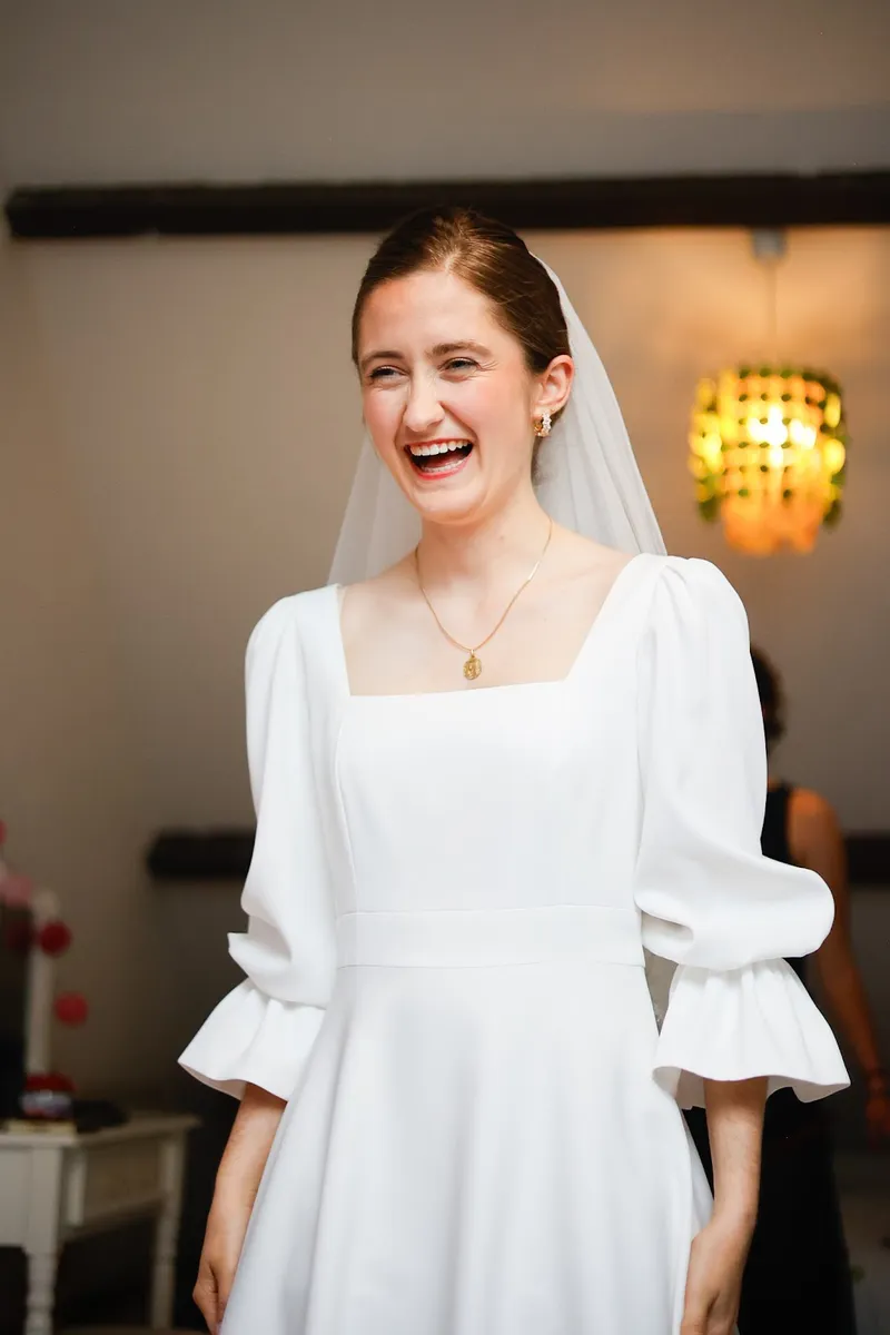 Amélie qui rit aux éclats, robe de mariée sur mesure à col carré et manches bouffantes à volants, voile court